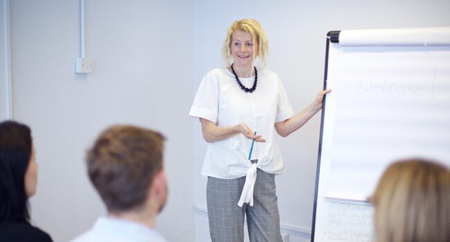Jen with flip chart presenting to a team
